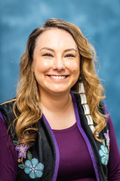 a portrait of a woman wearing a beaded vest and a purple shirt